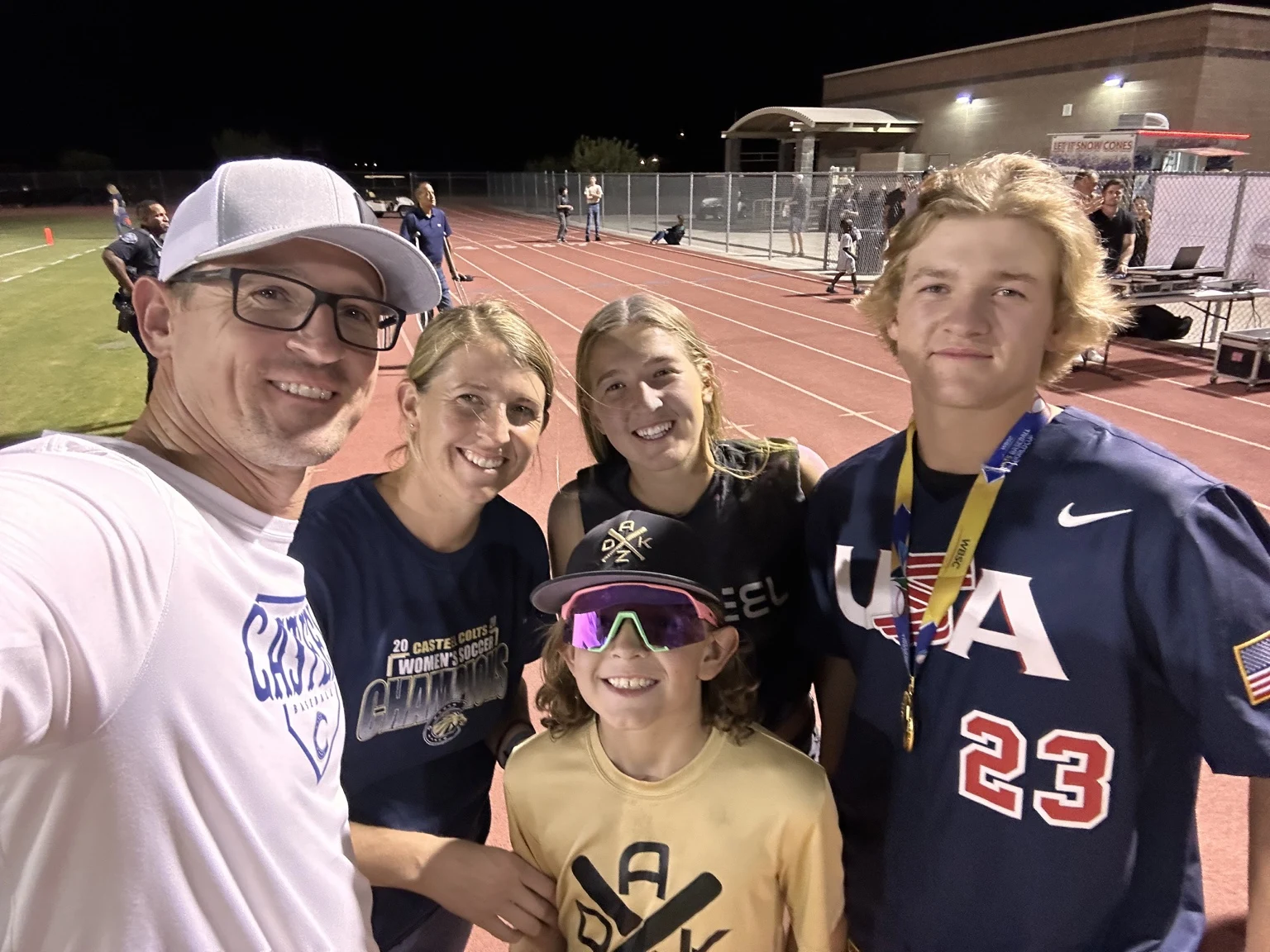 A Harwood family selfie beside a track and ballfield at night