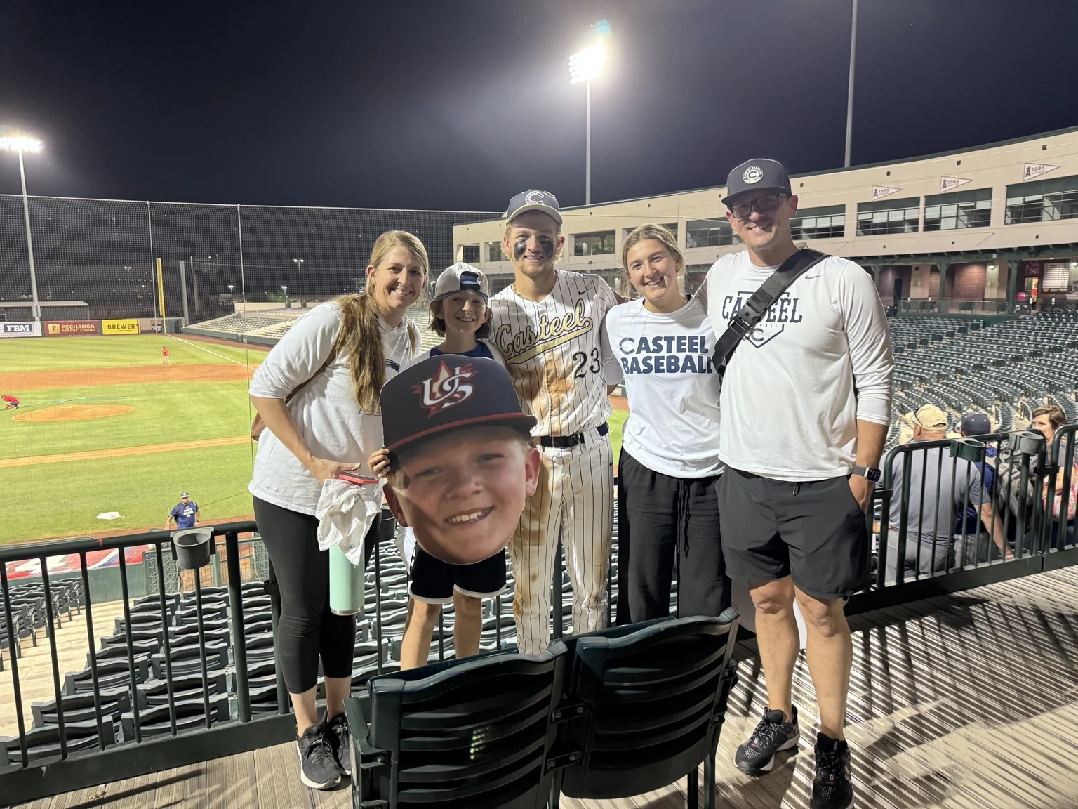 The Harwood family together beside a baseball field at night