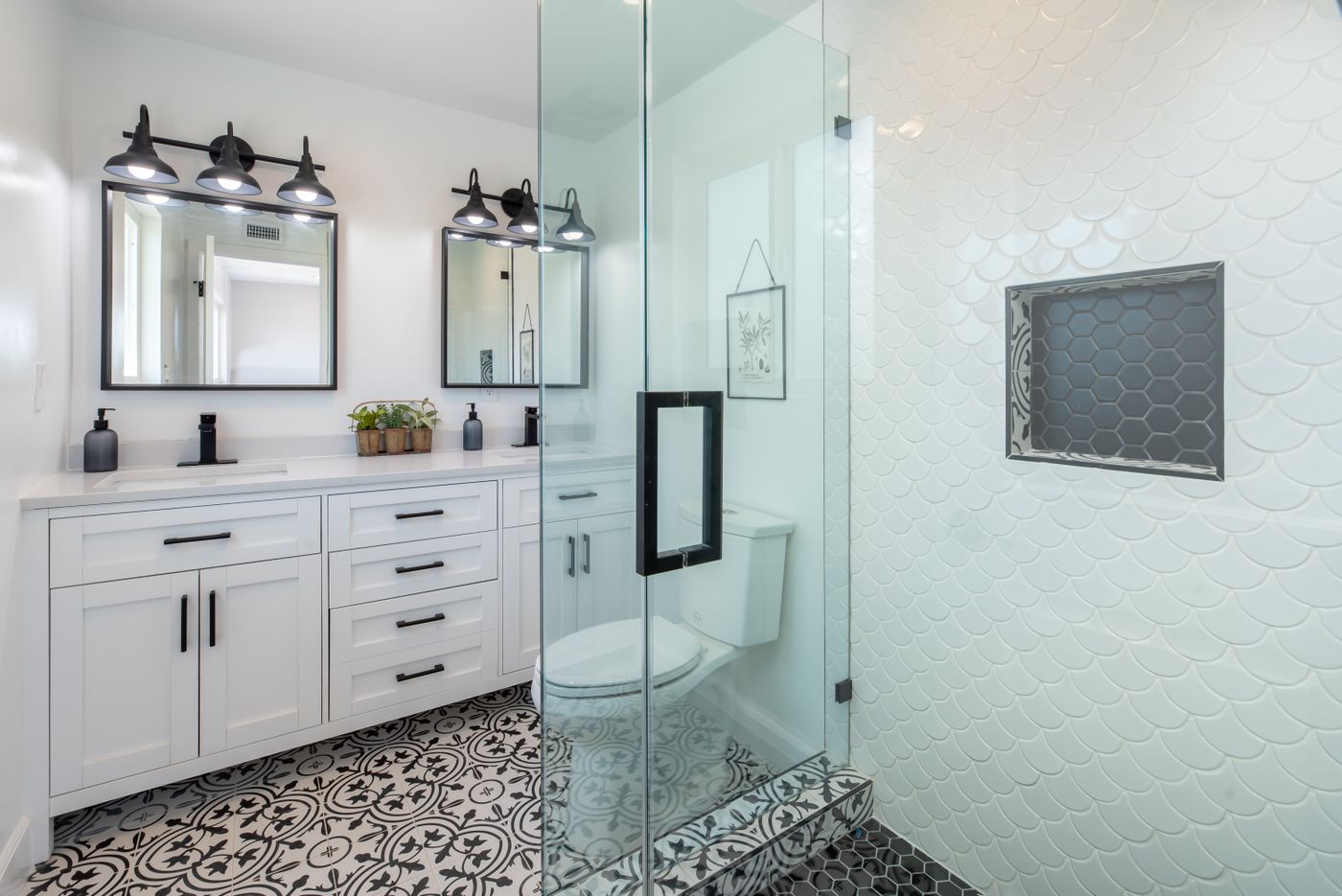 A clean white bathroom with a glass shower and patterned tile