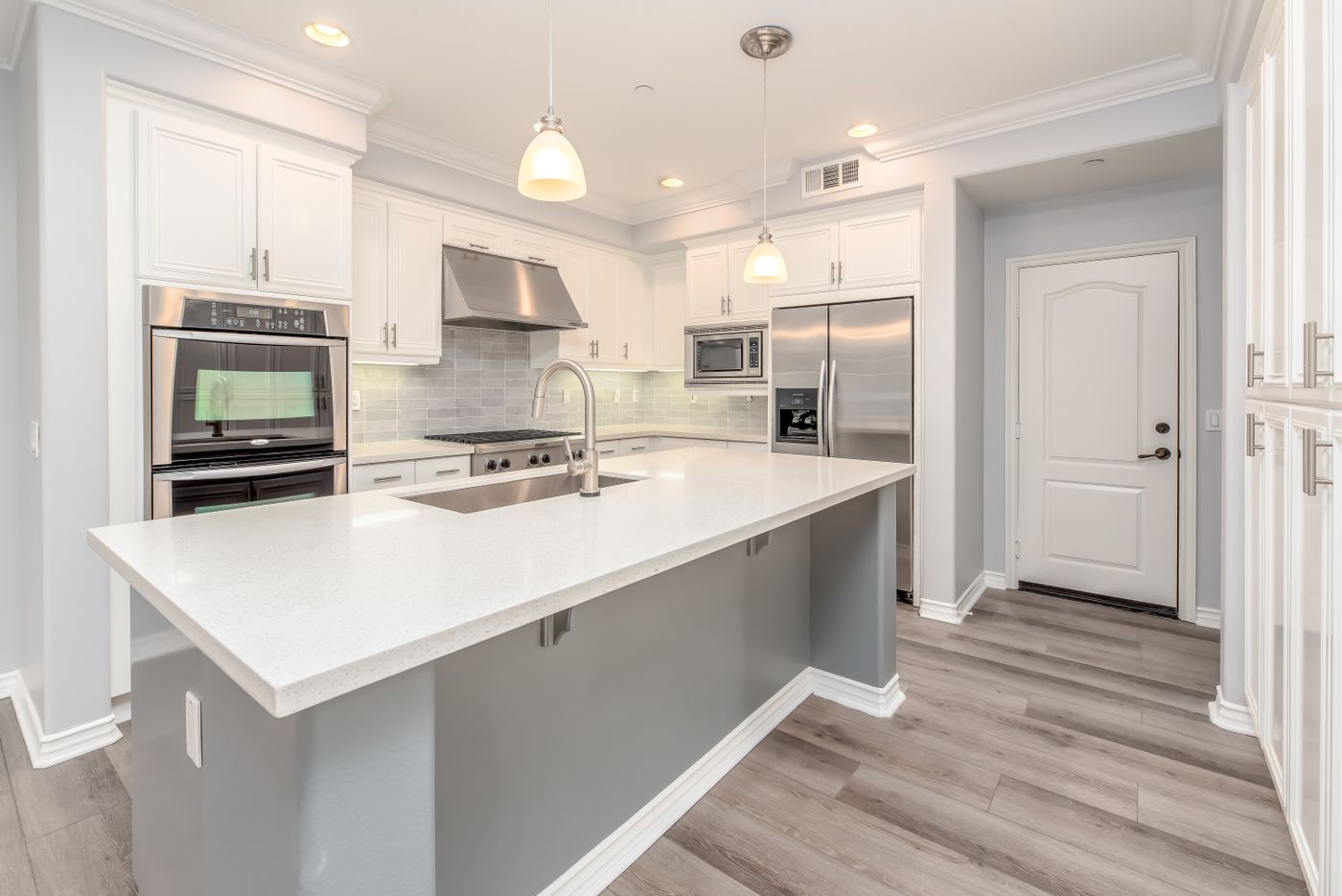 A bright white kitchen with an island and warm wood flooring