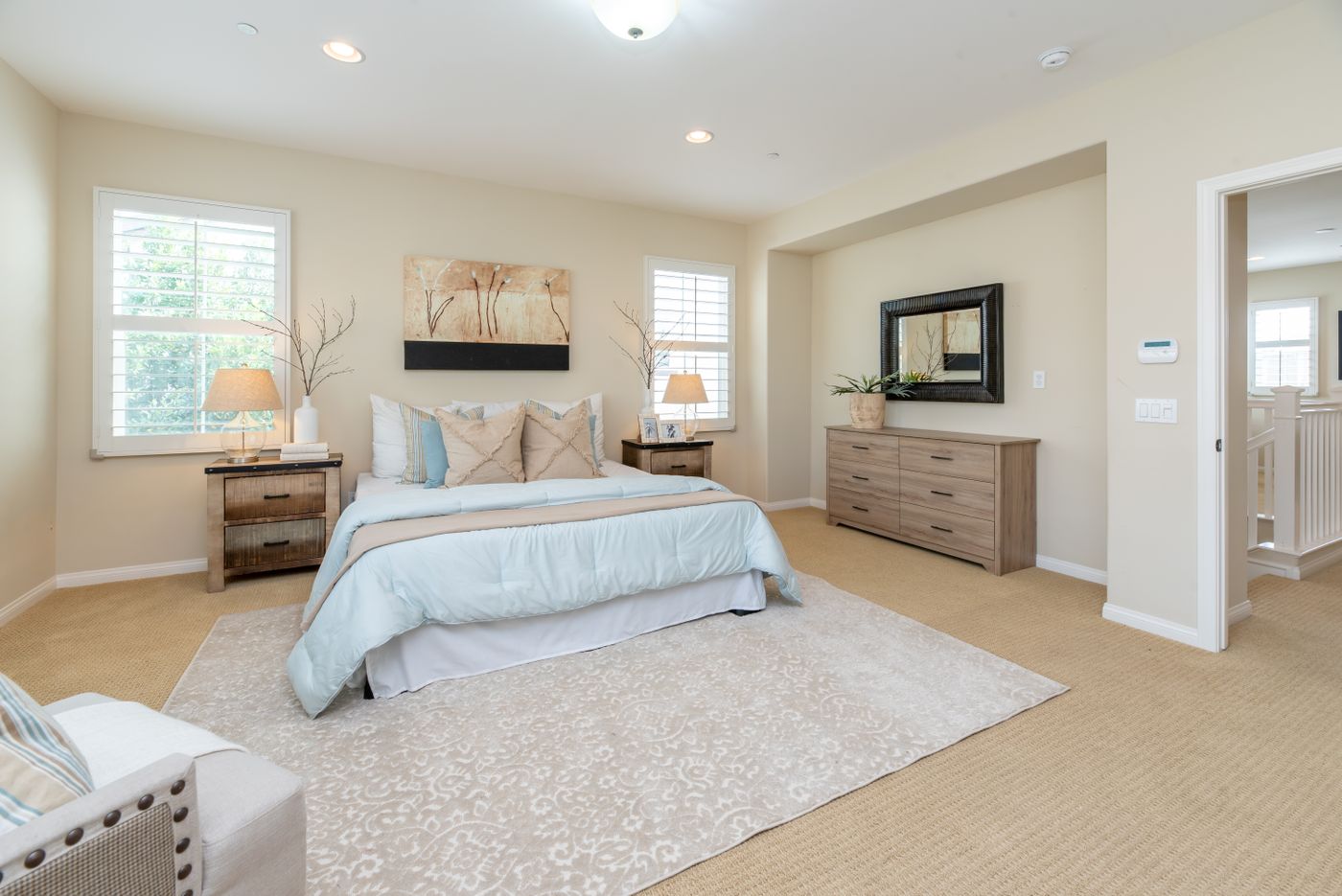 A bright bedroom with cream bedding, neutral furniture and warm natural light