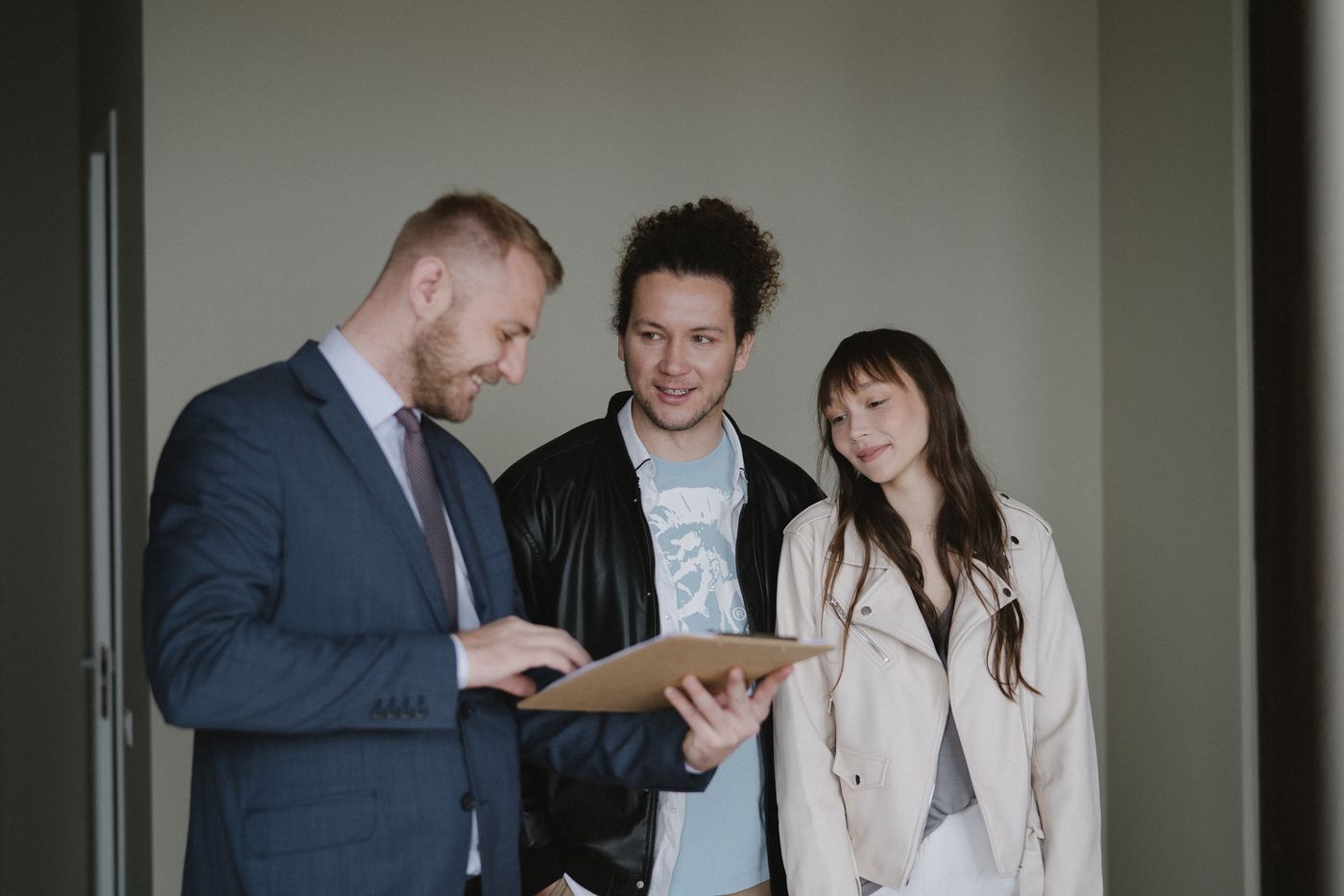 A smiling couple discussing paperwork with a real estate professional