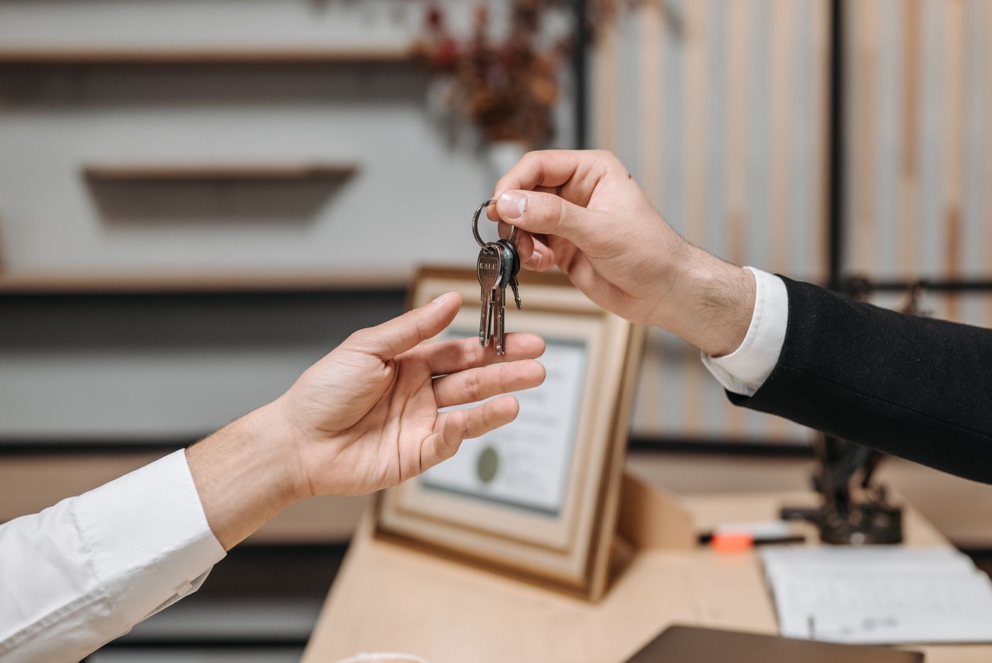 Close view of hands passing a set of keys across a desk