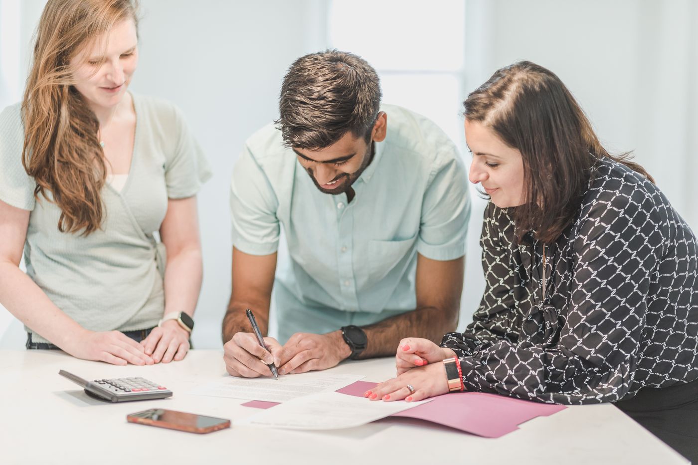Three adults reviewing and signing a property document