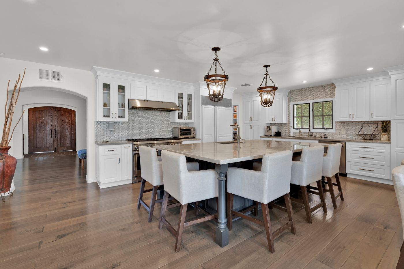 A spacious kitchen with white cabinets, island seating and warm accents