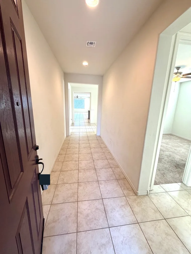 View from an open front door into a tiled hallway and adjoining room, with lockbox labels obscured