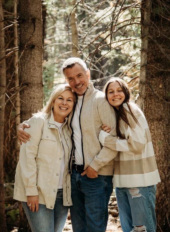 Judy, Paul and Reese together in the woods in their 2023 family portrait